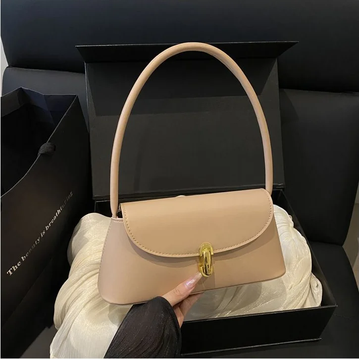 Nude Baguette Bag — Nude baguette handbag with a short top handle and gold turn clasp